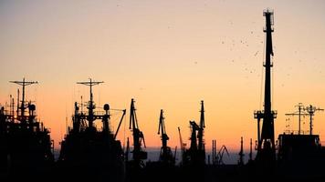 silhouettes de navires et de grues à conteneurs dans le port maritime photo