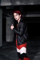 un asiatique homme avec rouge cheveux et une noir veste est posant dans un abandonné bâtiment photo