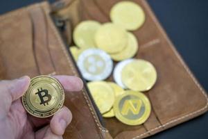 main en portant crypto-monnaie pièces de monnaie sur portefeuille. bitcoin sur bois bureau table Contexte. virtuel crypto-monnaie concept. numérique pour defi décentralisé financier bancaire p2p échange investissement La technologie photo