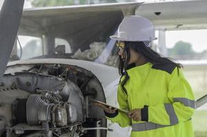 technicien fixant le moteur de l'avion, génie aérospatial féminin vérifiant les moteurs d'avion, maintenance mécanique asiatique inspecte le moteur d'avion photo