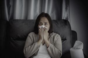 asiatique malade femme asseoir sur le canapé rester à maison, la femme se sentait mauvais, voulait à mensonge vers le bas et repose-toi, prends médicament photo