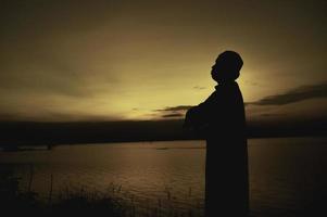 silhouette Jeune asiatique musulman homme prier sur coucher de soleil, ramadan Festival concept photo