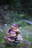 magnifique gâteau fabriqué de coloré beignets et été fleurs. je a pris cette image de le gâteau sur une gros moussu Roche dans le jardin. photo