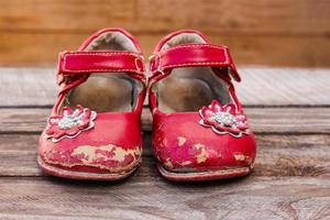 vieux rouge bébé des chaussures sur en bois Contexte. photo