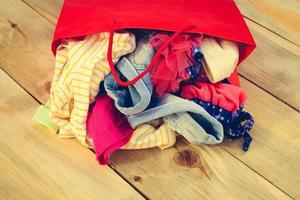 aux femmes Vêtements chutes en dehors de papier achats Sacs sur en bois Contexte. photo