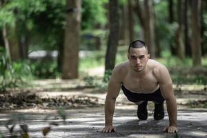 Beau homme des exercices par pendaison sur une bar Extérieur, asiatique homme les trains pour sportif événements photo