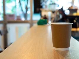 un café tasse papier mis sur une en bois tableau, dans une café café magasin les boissons sont disponible. chaud à l'intérieur pour à emporter prêt à boire, rafraîchissant. arôme éveillé Frais à travail mis photo