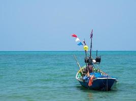 vue paysage petit bateau de pêche en bois vieux garé côte la mer. après la pêche des pêcheurs dans petit village c'est la petite pêcherie locale. ciel bleu, nuages blancs, temps clair, plage de phala, rayong photo