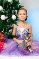 fille dans violet robe en portant de race sphynx chauve chat est assis près Noël arbre photo