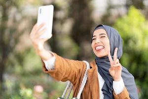 musulman femme taling une selfie tandis que faire des gestes la victoire avec les doigts photo