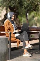 musulman femme en utilisant une portable et écouteurs en plein air photo