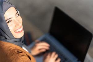 Haut vue de une souriant musulman femme travail avec portable photo