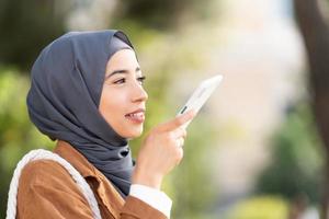 musulman femme Envoi en cours une voix message en plein air photo