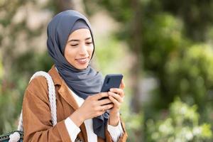 souriant musulman femme en utilisant une mobile. proche en haut photo