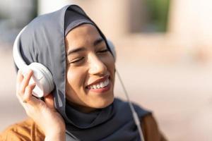 musulman femme profiter tandis que écoute à la musique en plein air photo