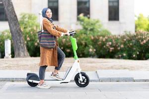 musulman femme posant tandis que en utilisant un électrique scooter photo