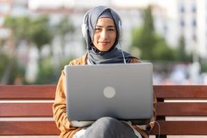 portrait de une musulman femme en utilisant une portable photo