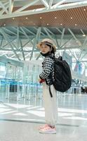 mignonne content enfant fille avec sac à dos à aéroport Terminal. enfant et famille en voyageant vacances pour attendre embarquement dans Terminal. famille Voyage concept. photo