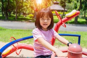 de bonne humeur enfant fille en jouant sur terrain de jeux dans le parc. en bonne santé été activité pour les enfants. photo