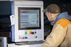 une meubles production ouvrier derrière une programmé machine fait du meubles les pièces. meubles fabrication. photo