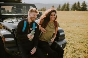 couple souriant préparant une aventure de randonnée avec des sacs à dos en véhicule tout-terrain photo