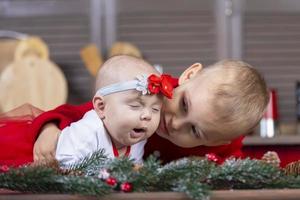 le peu frère regards à le bâillement nouveau née sœur. marrant des gamins à Noël temps. photo