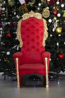 rouge trône à le Noël arbre. fauteuil pour Père Noël claus. photo