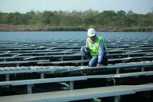 ingénieur inspecteur en portant portable et travail dans solaire panneaux Puissance plante vérification photovoltaïque cellules et électricité production. photo