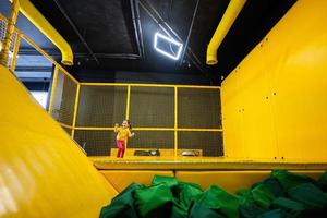 peu fille enfant sauter sur trampoline à Jaune terrain de jeux parc. enfant dans mouvement pendant actif divertissements. photo