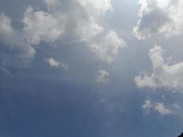 nuages blancs dans le ciel bleu. beau fond bleu clair. peu nuageux, beau temps. nuages bouclés par une journée ensoleillée. photo