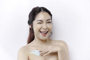 peau se soucier des produits concept. asiatique femme appliquant hydratant lotion sur corps après douche, permanent enveloppé dans serviette, tondu image photo
