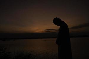 silhouette Jeune asiatique musulman homme prier sur coucher de soleil, ramadan Festival concept photo