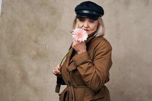 élégant personnes âgées femme dans manteau en portant une fleur mode photo