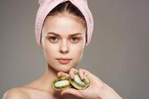 femme avec rose serviette sur sa tête nu épaules tondu vue de kiwi fruit dans santé main photo