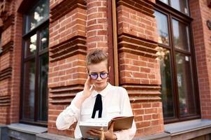 court aux cheveux femme avec des lunettes en marchant autour le ville avec une livre mode de vie photo