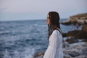 femme dans blanc robe avec humide cheveux par le océan inchangé photo