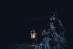 triste enfant fantôme à nuit, halloween Festival idée, vendredi 13ème, horreur film scène, une fille avec poupée photo