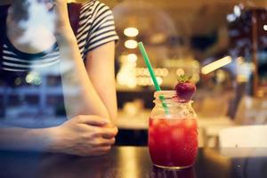 une femme dans des lunettes avec une court coiffure est assis seul dans une restaurant cocktail photo