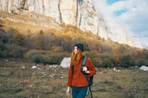 une voyageur dans une chandail jeans avec une sac à dos sur le retour et une chaud chapeau montagnes l'automne paysage photo