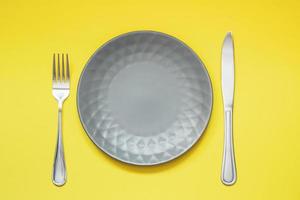 Assiette grise vide et couverts sur fond jaune photo