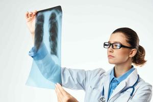une infirmière dans une blanc manteau à la recherche à un radiographie professionnel examen photo