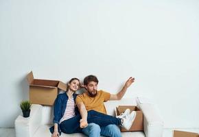 Jeune couple sur blanc canapé avec des boites de amusement bavardage photo