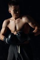 Masculin athlète boxe gants sur noir Contexte faire des exercices photo