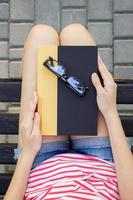 une Jeune femme en portant une livre avec noir des lunettes pour en train de lire dans le parc. photo