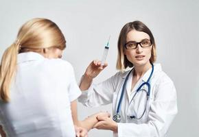 femelle médecin donnant un injection à une effrayé femelle patient dans une blanc T-shirt photo