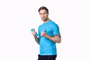gars avec haltères aller dans pour des sports dans une bleu T-shirt sur une lumière Contexte photo