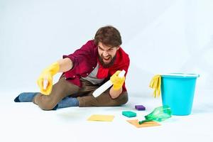 une homme dans une rouge imperméable séance à Accueil la lessive le planchers fournir prestations de service détergent accessoires photo