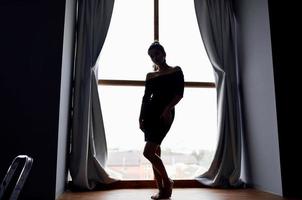 femme posant dans noir robe près fenêtre silhouette modèle photo