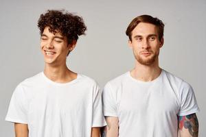 deux Hommes dans blanc t-shirts sont permanent suivant à relation amicale émotions photo