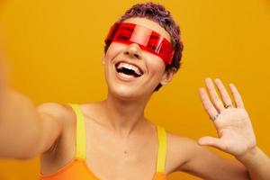 femme portant inhabituel millénaire des lunettes prise selfies dans tenue de sport contre un Orange studio arrière-plan, gratuit espace photo